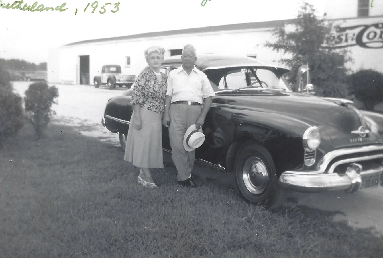 Alconia Sutherland Fleming and her brother Harry Sutherland standing beside a car in 1953