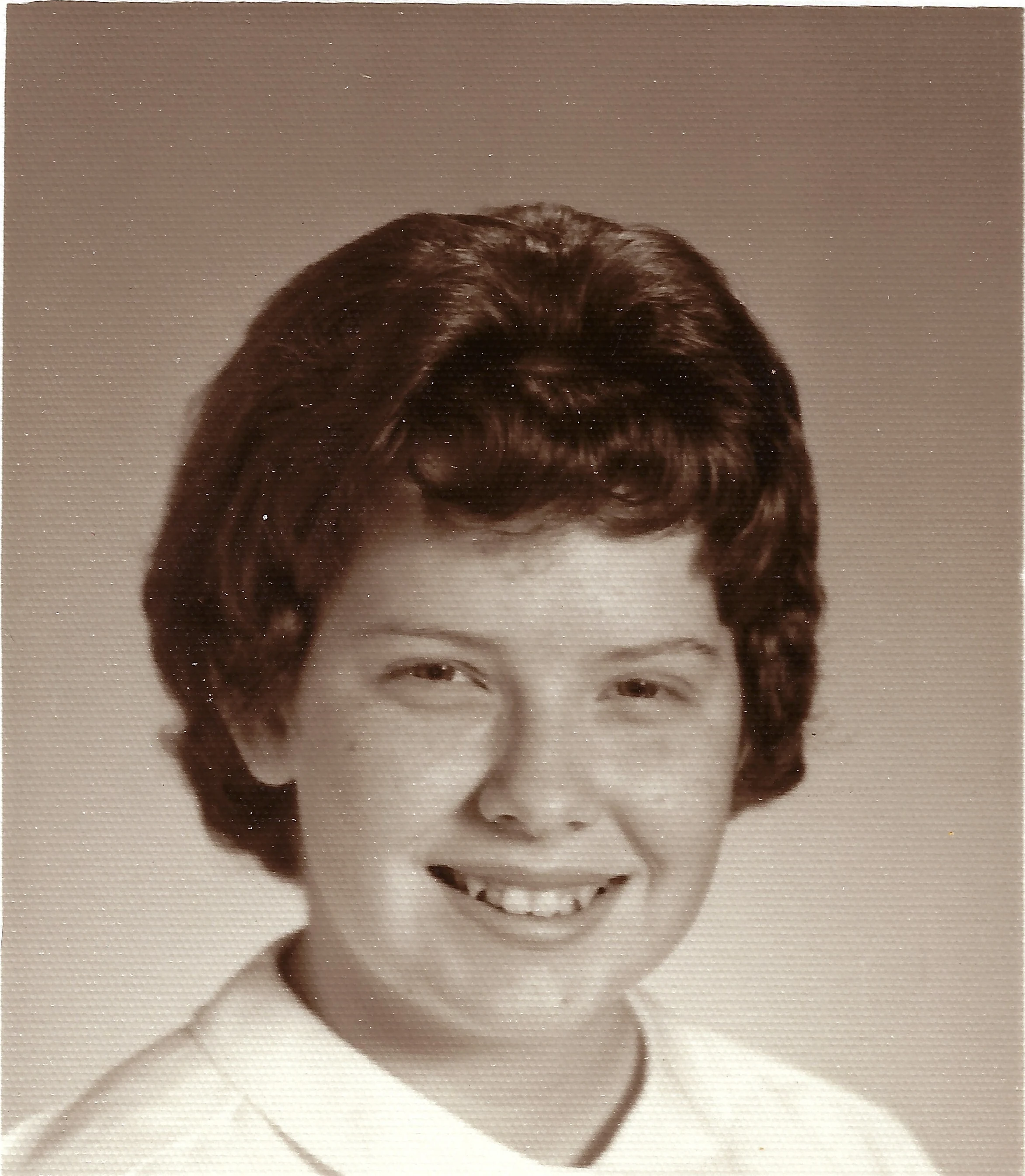 A sepia school portrait of Cacky as a smiling teenager, around 1962