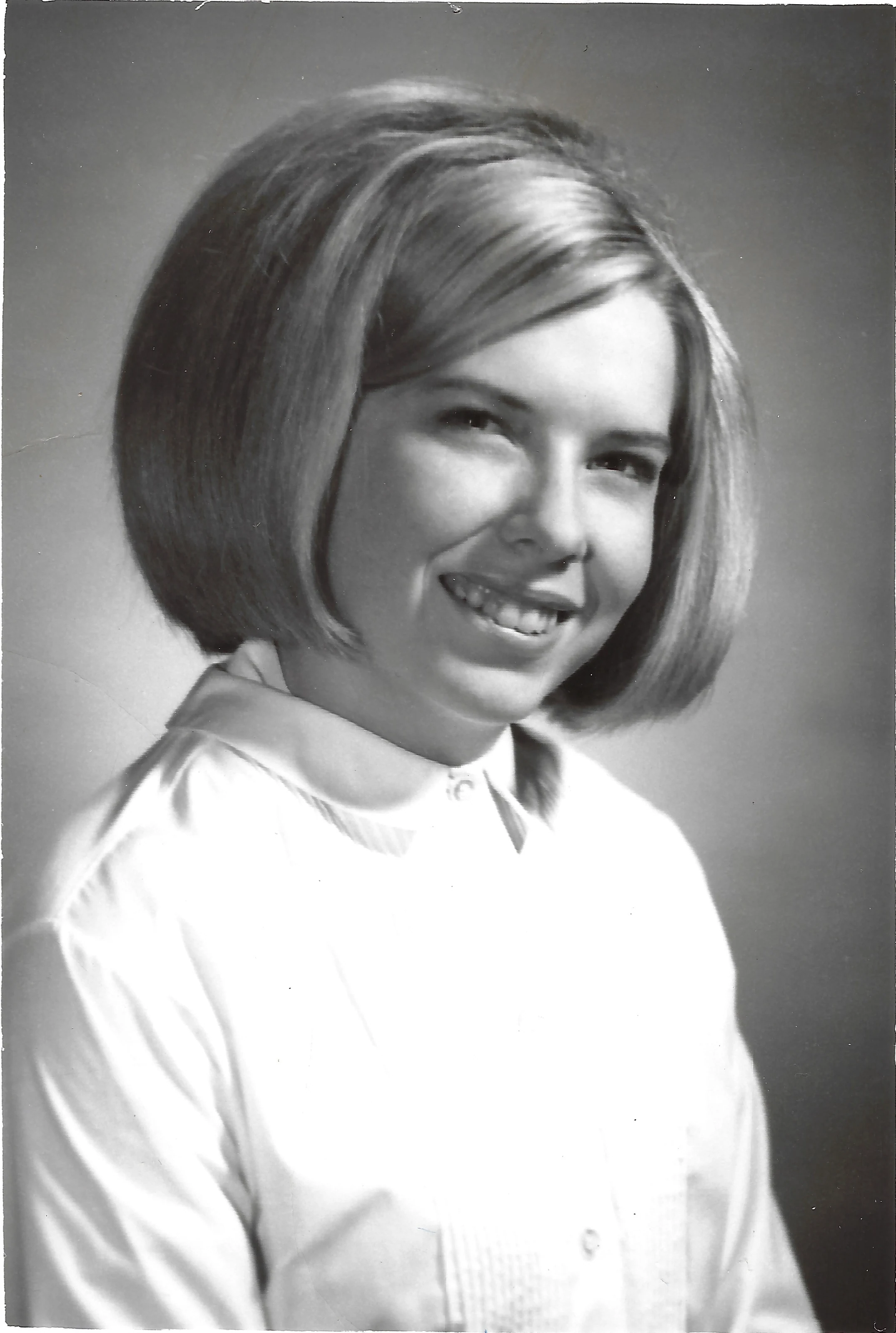 A black-and-white studio portrait of Cacky as a young woman with a bob in a white blouse, around 1966