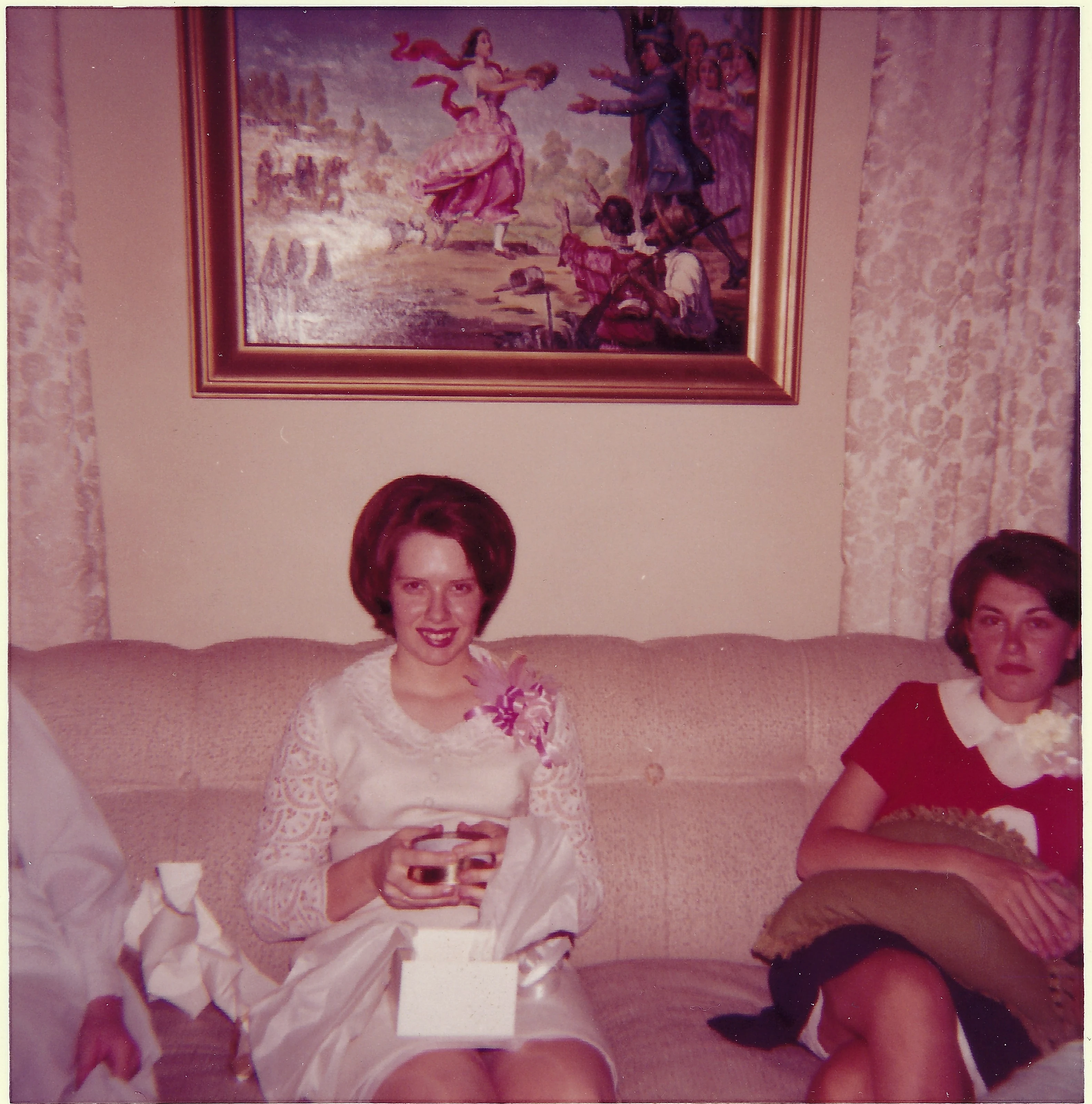 Cacky in her white lace graduation dress and corsage, seated on a couch at her high school graduation party on May 31, 1965