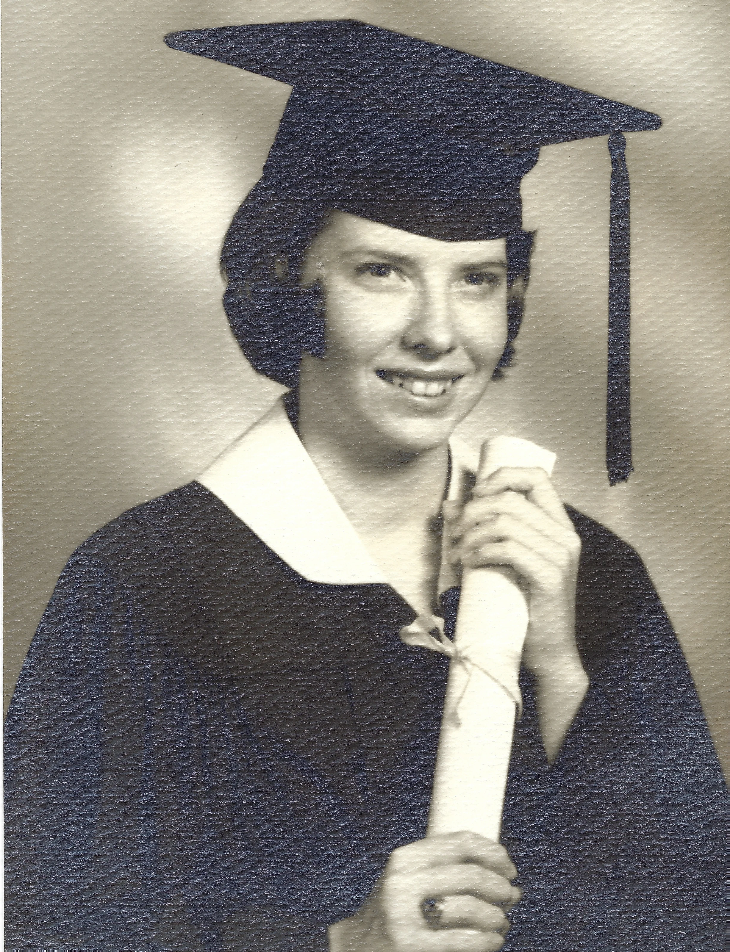 Cacky in a graduation cap and gown holding her diploma, around 1965