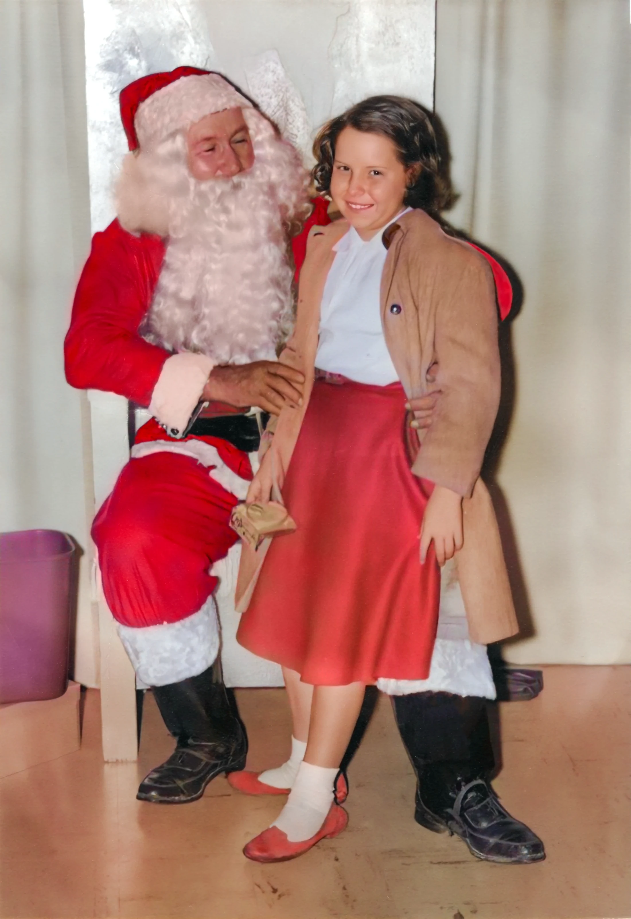 Cacky standing beside a seated Santa in 1960.