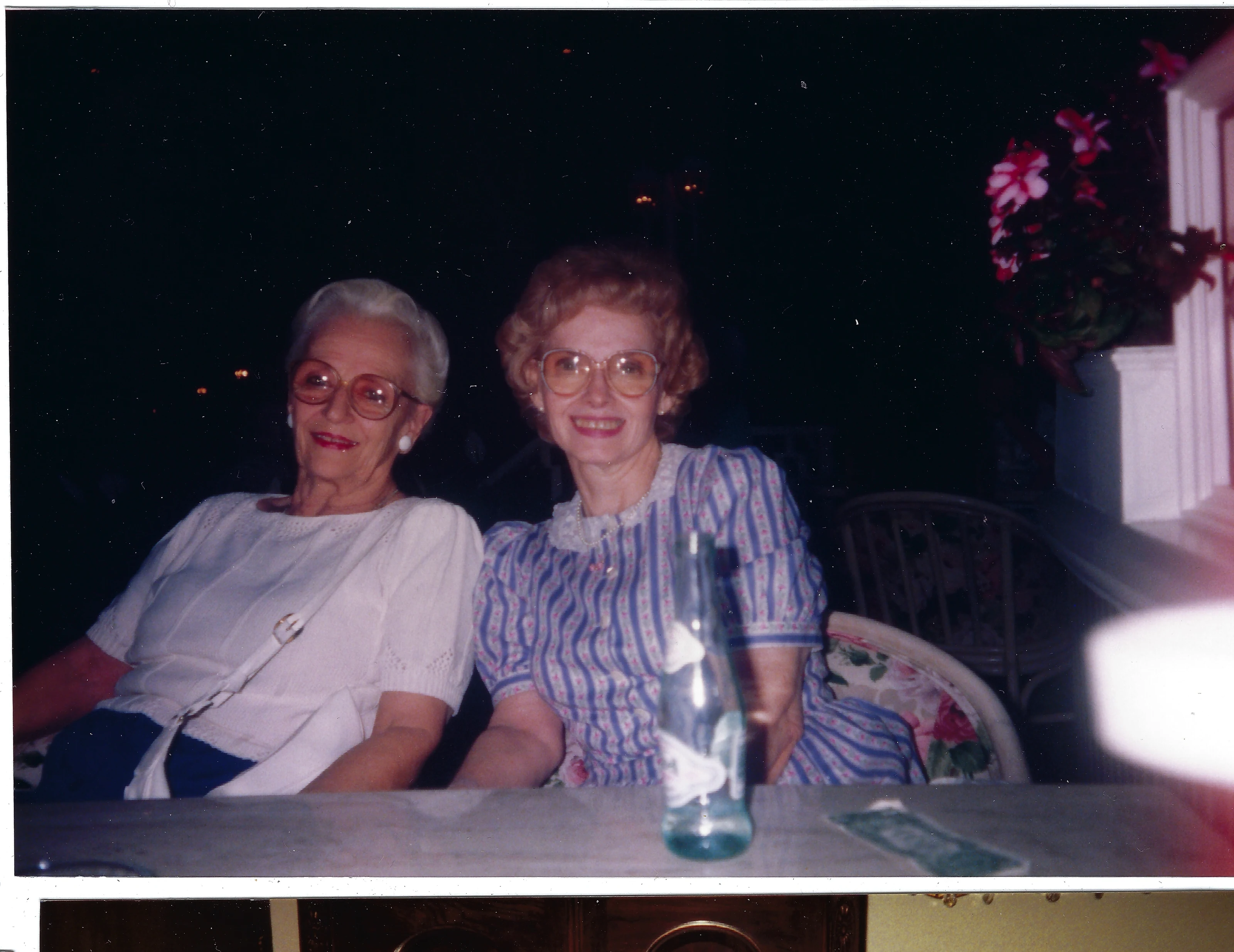 Gruzel (b.1924) and another woman smiling together at a table on an evening outing, around 1990