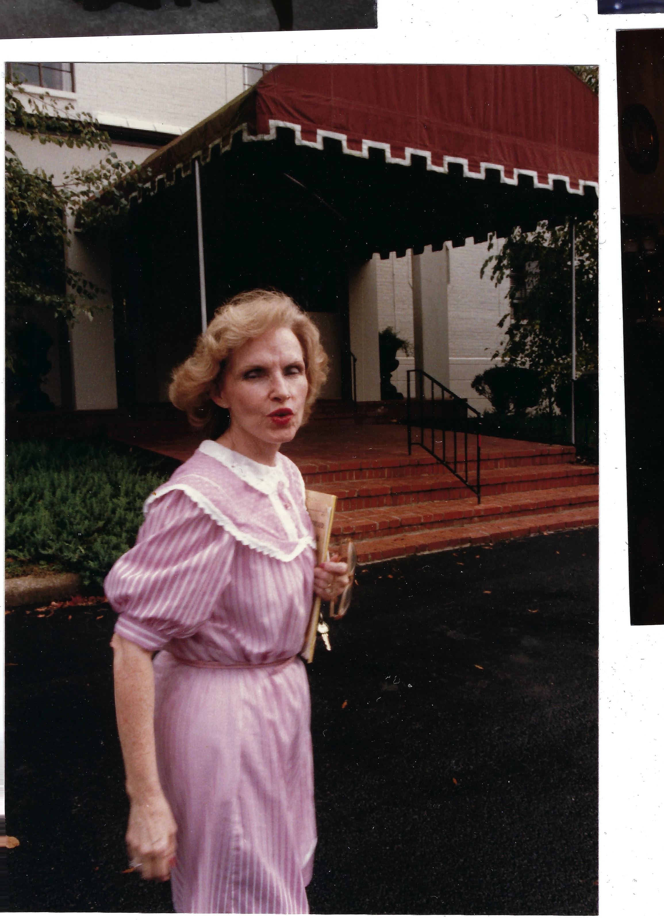 Gruzel (b.1924) in a pink striped dress standing outside a building with a striped awning, around 1990