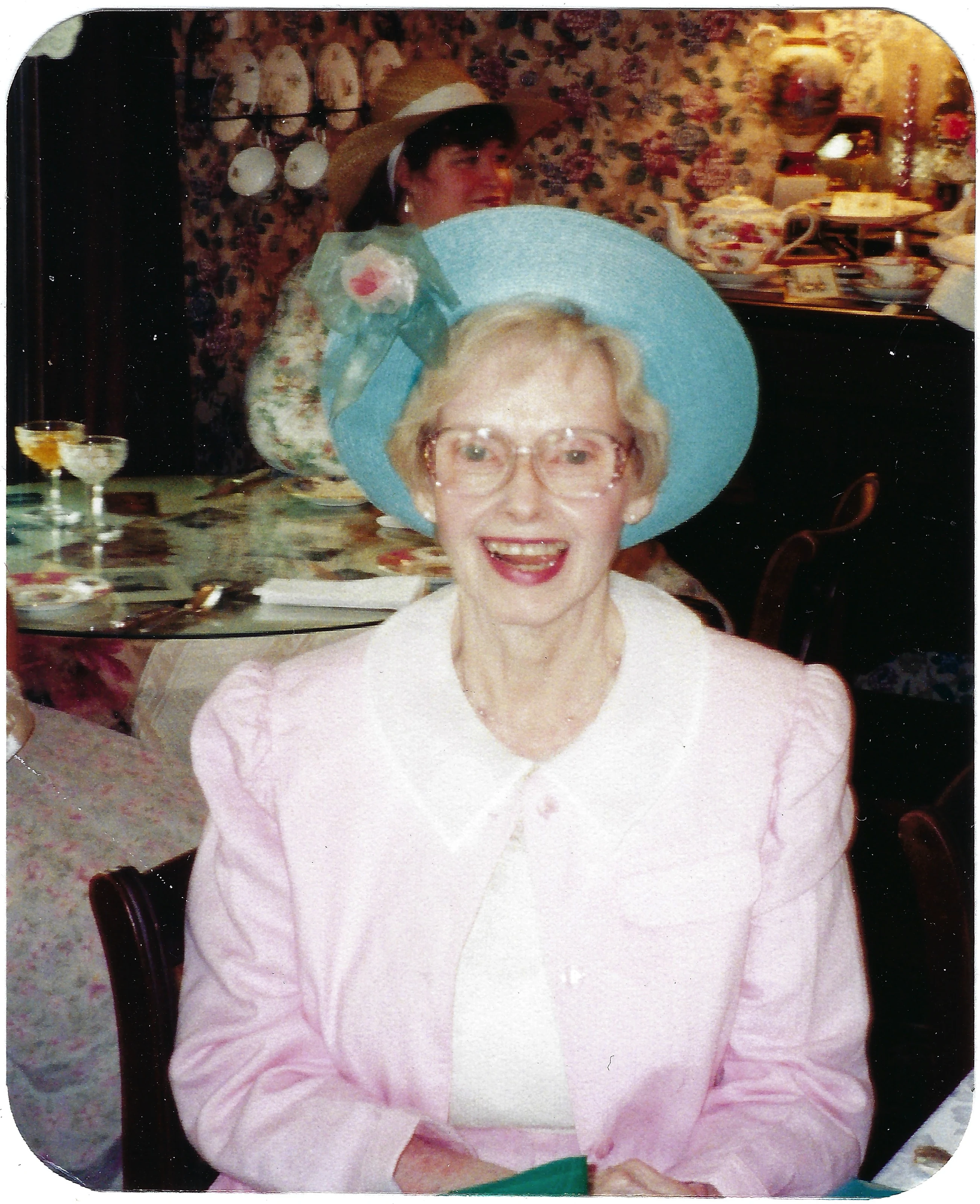 Gruzel (b.1924) in a pink suit and a wide blue hat at a tea party, around 1993