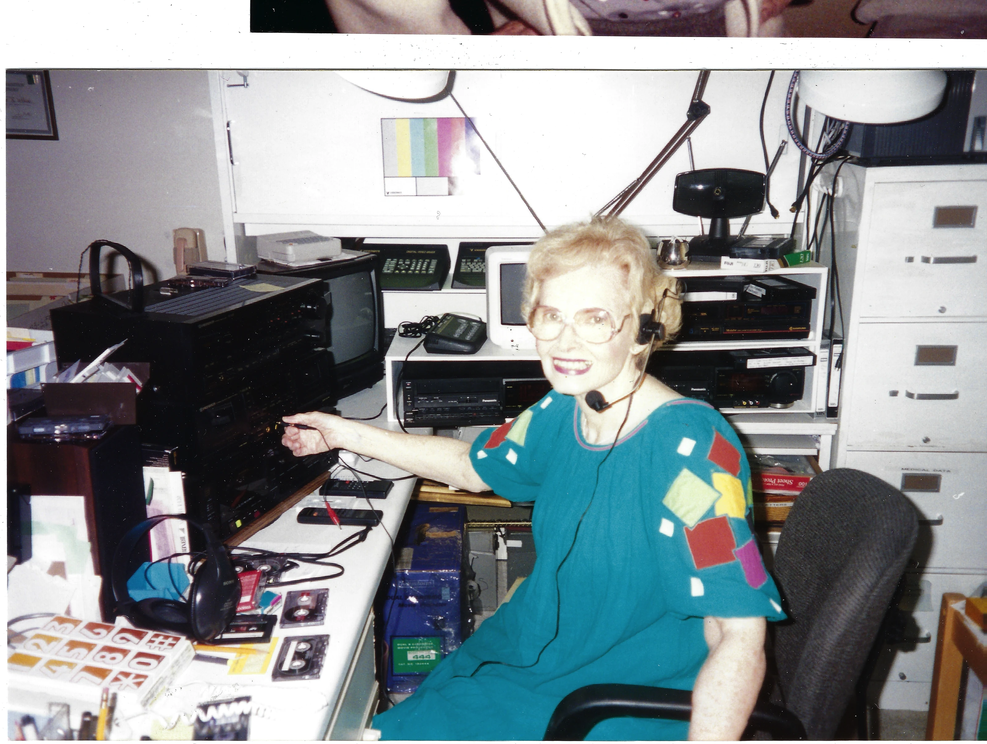 Gruzel (b.1924) in a headset at a desk of tape decks, monitors, and radio equipment, around 1993