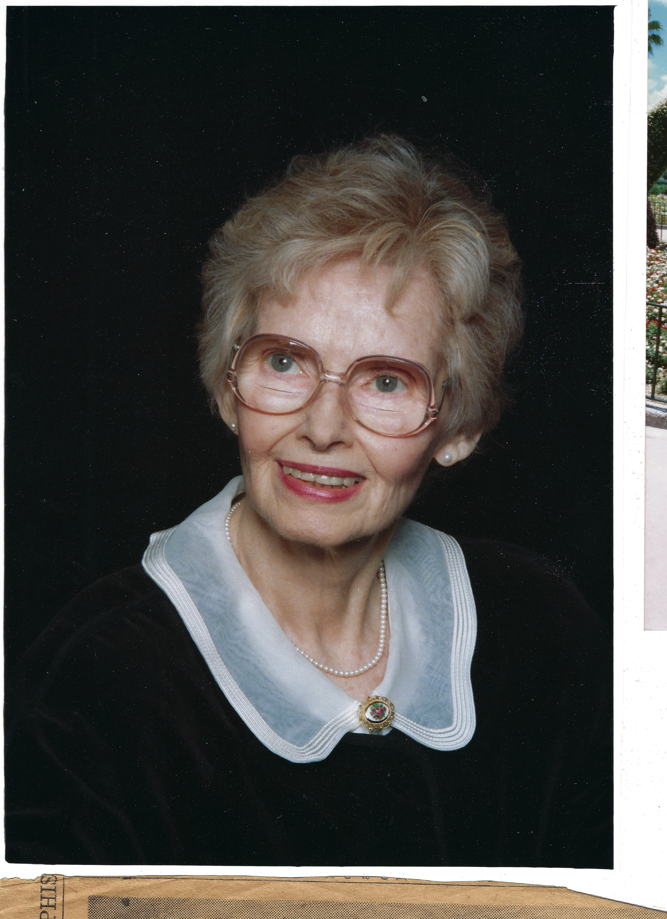 A color studio portrait of Gruzel (b.1924) in glasses, pearls, and a navy velvet dress with a white collar and cameo, around 1993