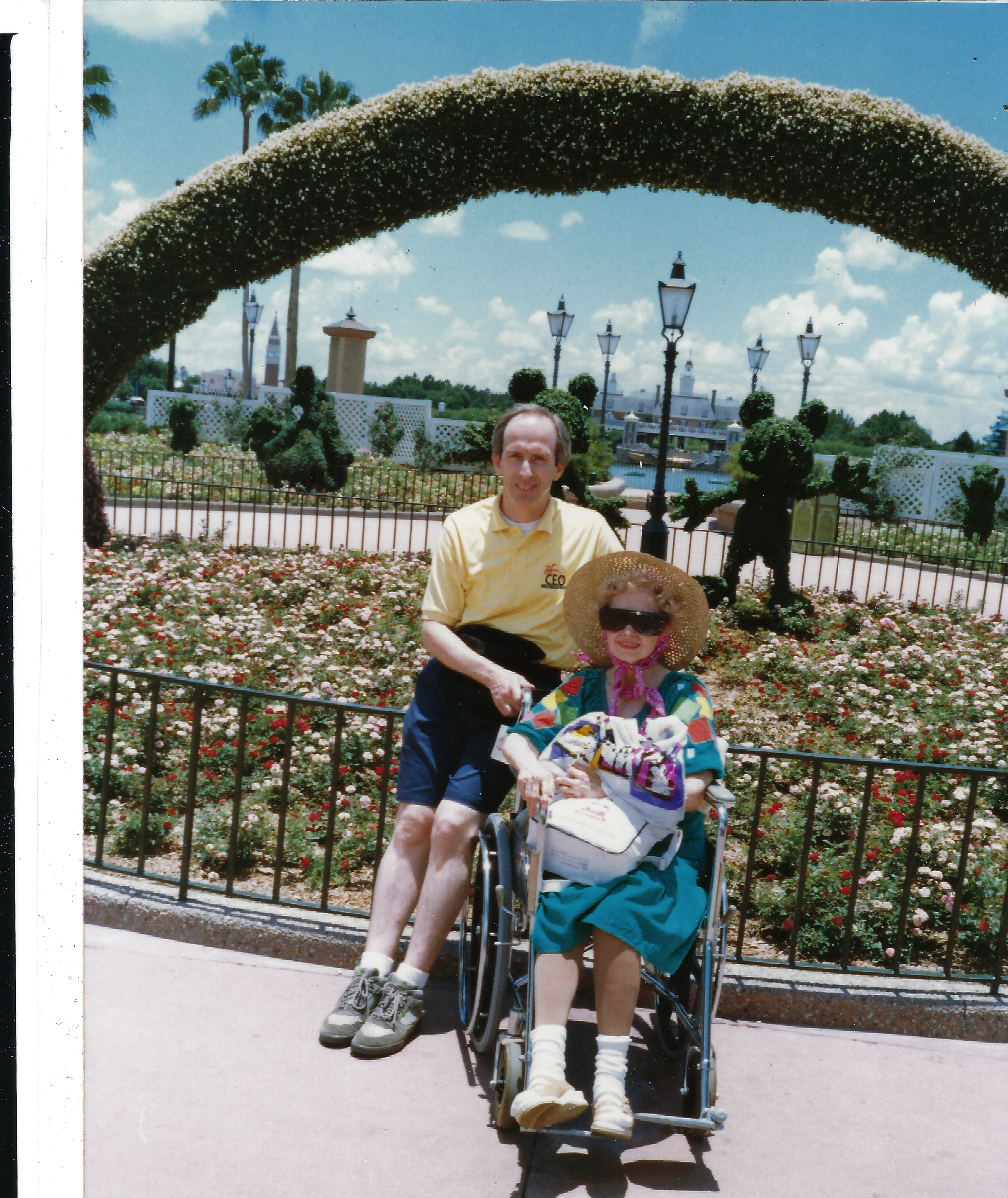 Gruzel (b.1924) in a wheelchair pushed by her son David Earle 'Uncle Son' Wilkins beneath a rose-garden arch at Epcot, Walt Disney World, around 1990