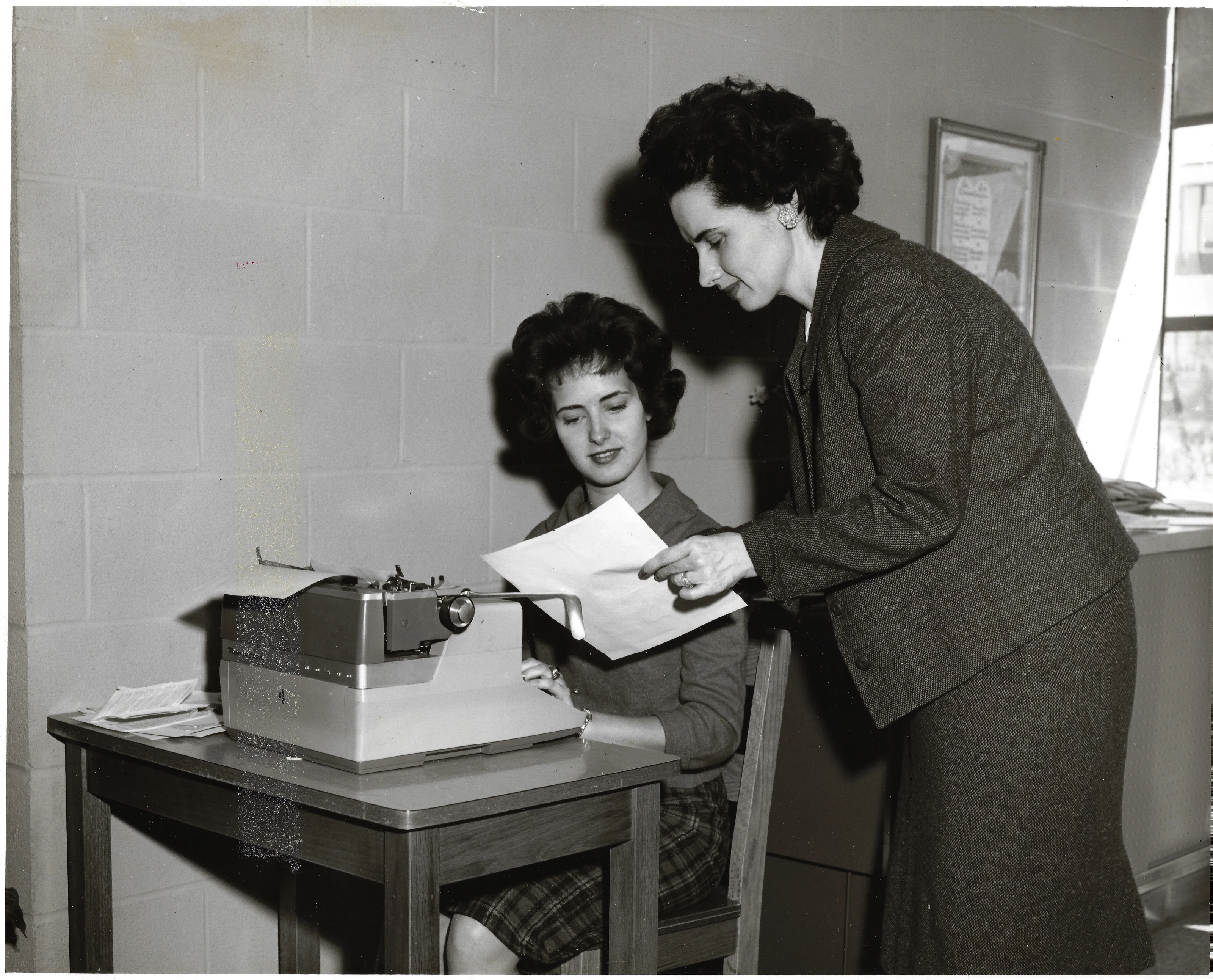 Gruzel (Mrs. Wilkins) helping a seated student at a typewriter, around 1962