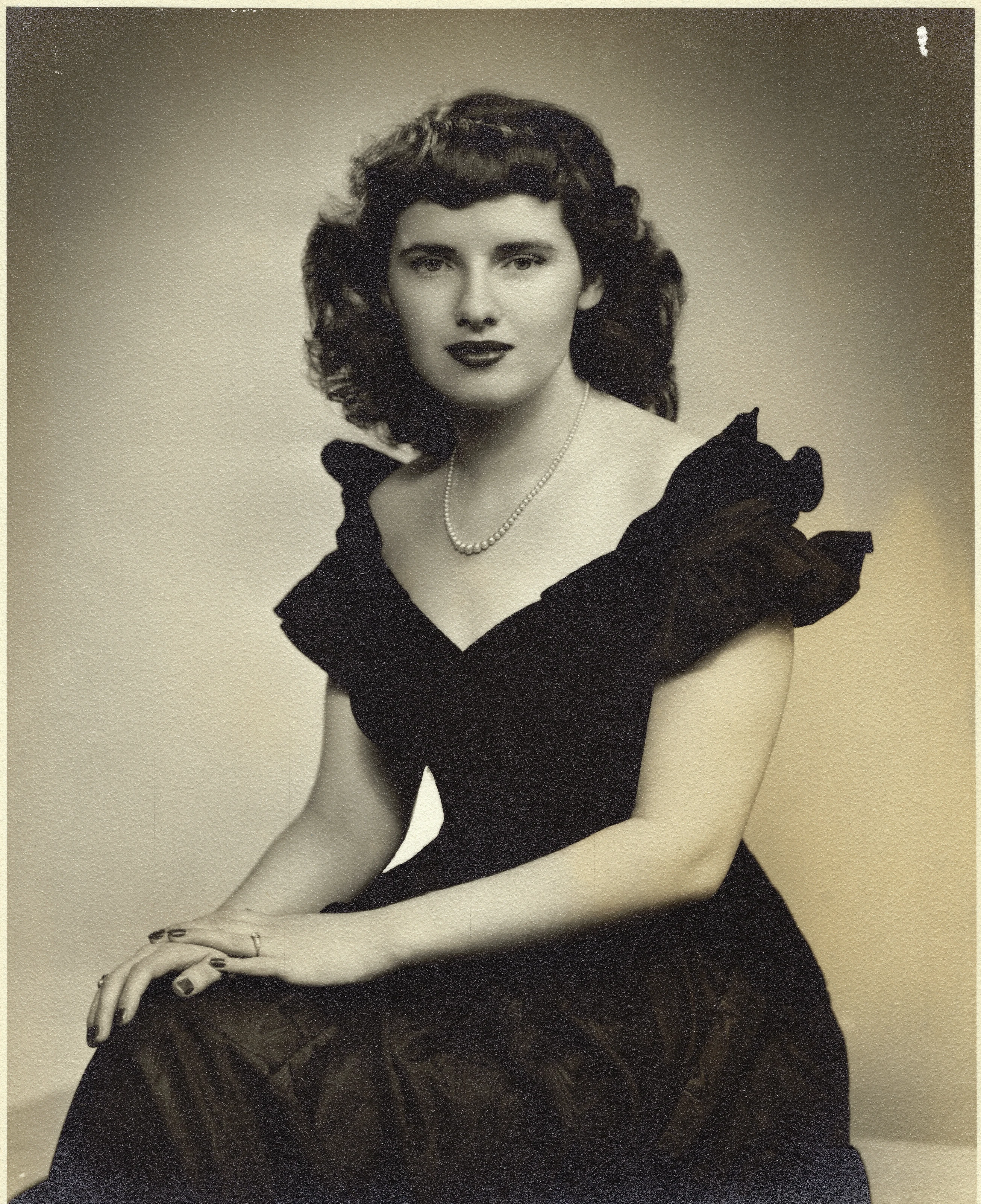 A 1940s studio portrait of Gruzel (b.1924) seated in a dark ruffled dress with a pearl necklace, around 1943