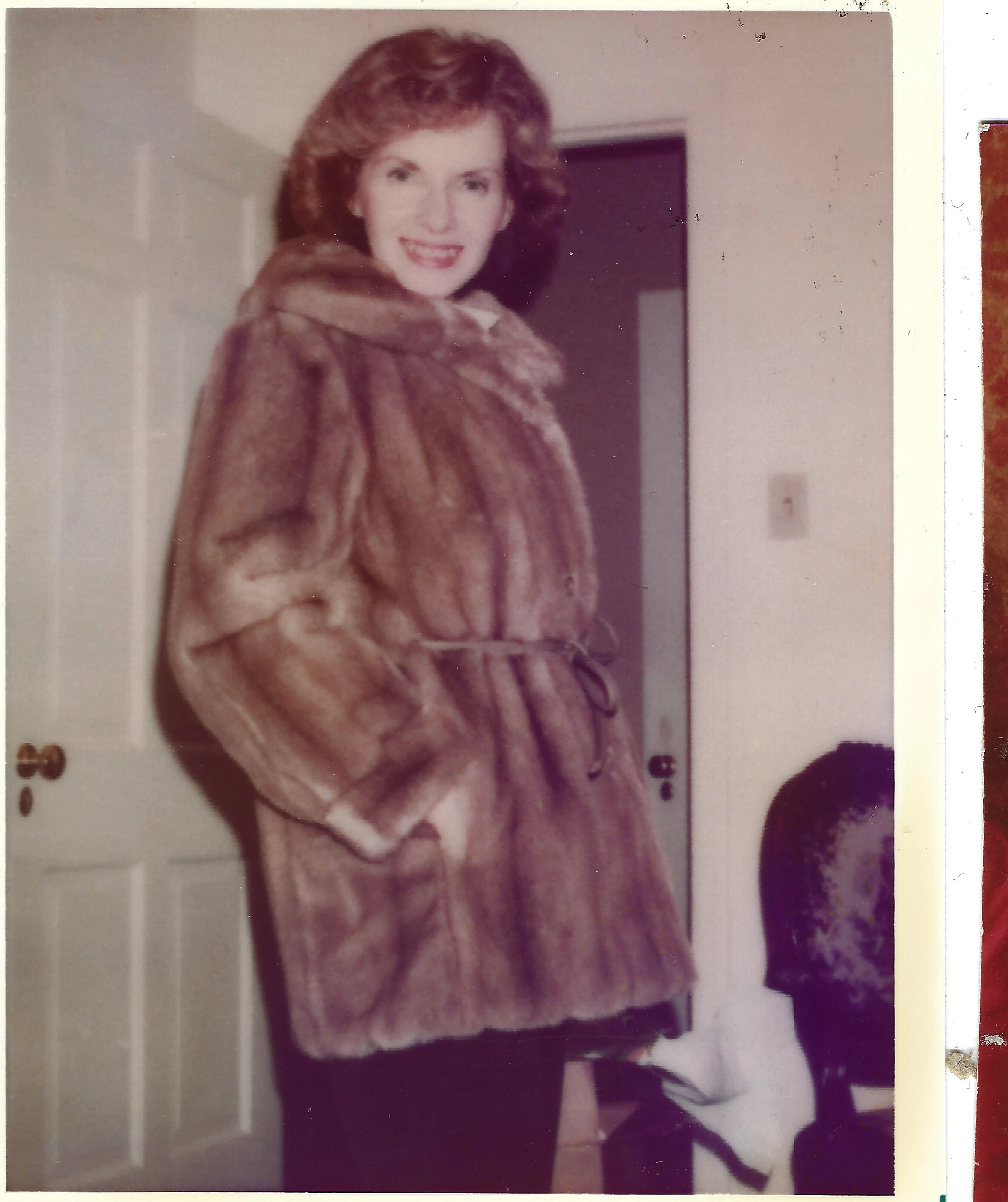 Gruzel (b.1924) smiling in a fur coat indoors, around 1977