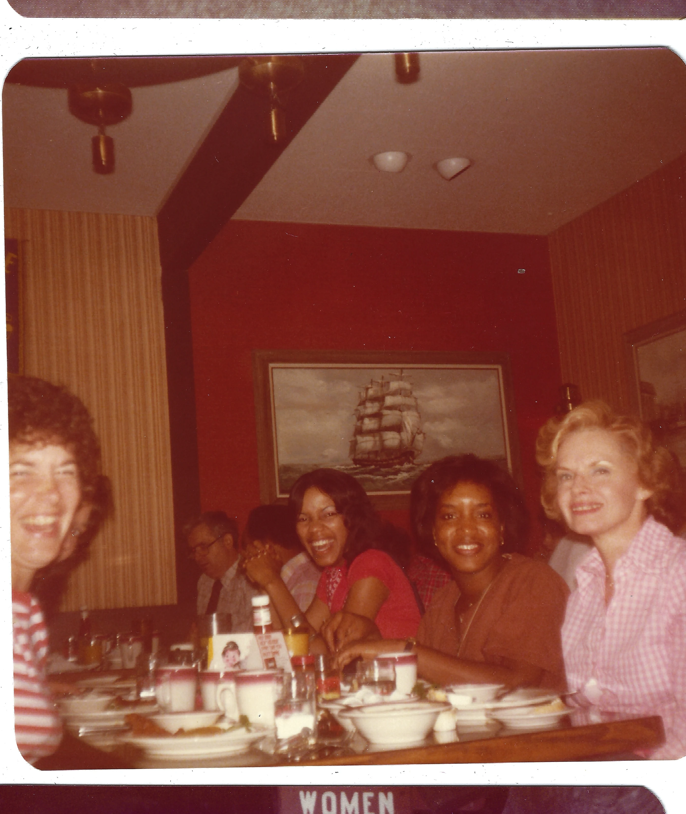 Gruzel (b.1924) with a group of women smiling around a restaurant table, around 1983
