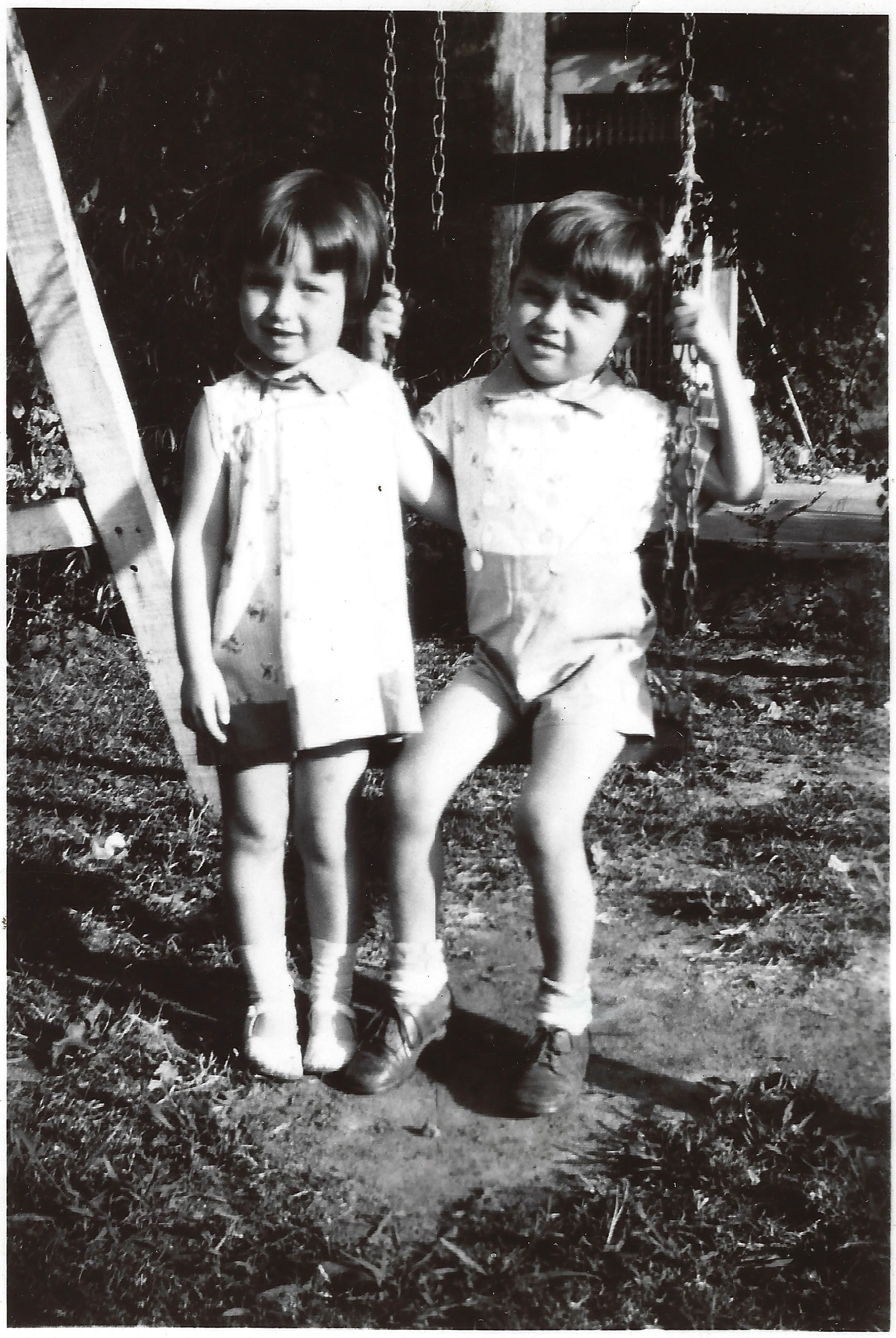 Gruzel and her older brother Kenny as small children seated together on a swing outdoors, around 1927