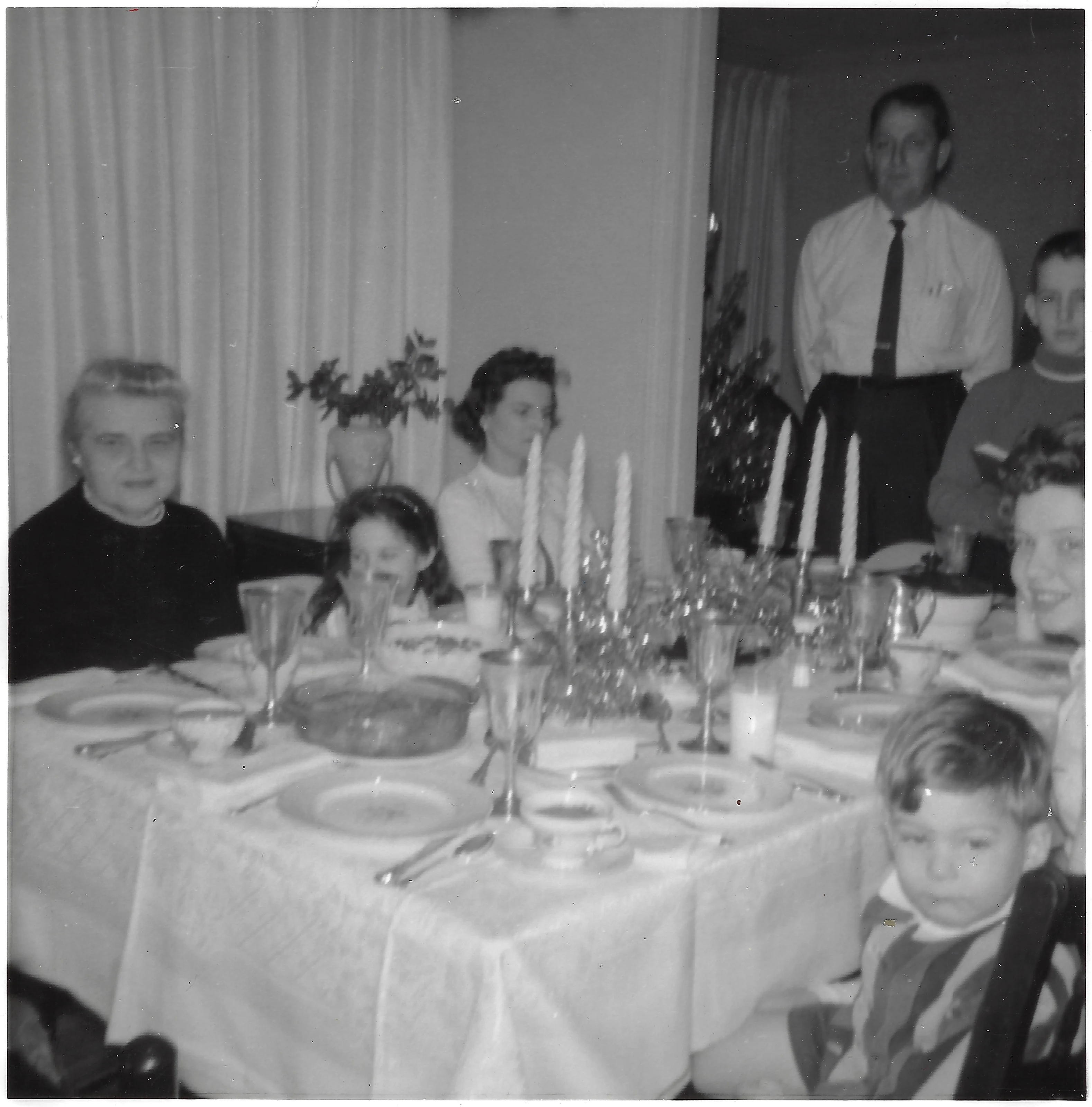 A family holiday dinner table set with candles; Big Goose, David E. Wilkins, Cacky and Mama Percy among the family, around 1964