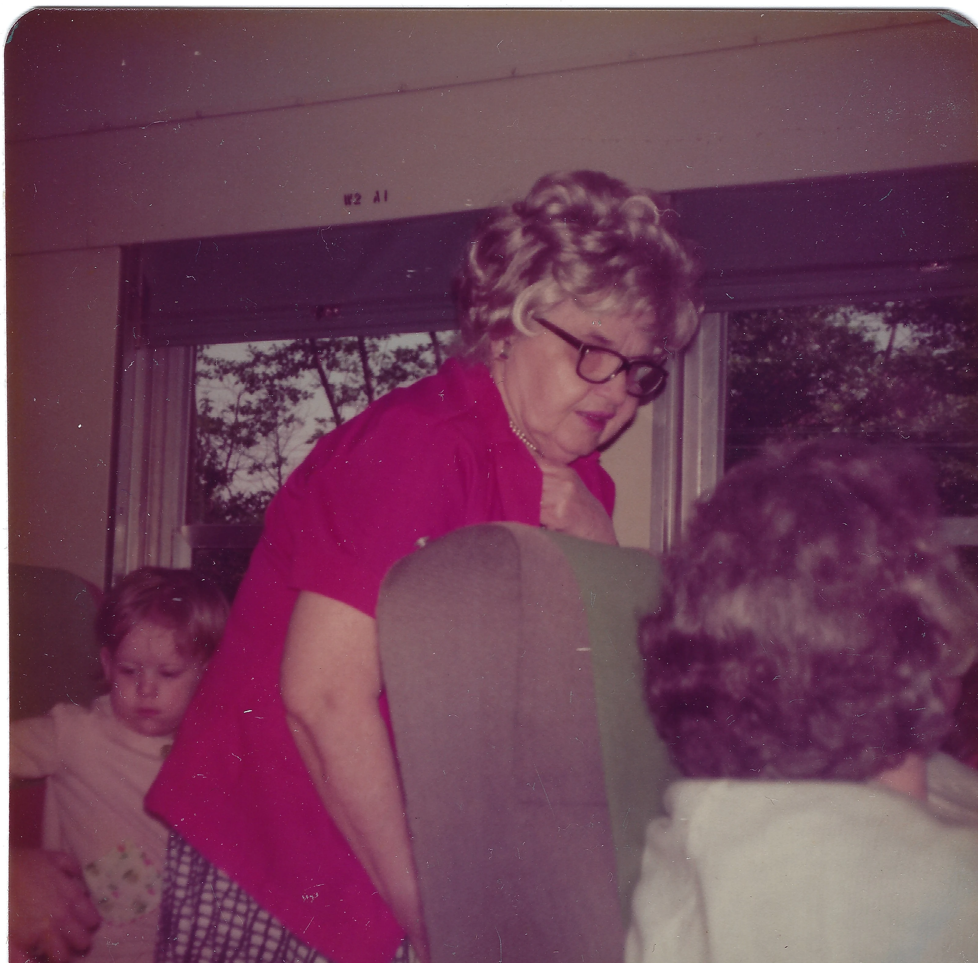 Mama Percy (Catherine Fleming) in a pink top leaning over a chair with young Jennifer nearby, around 1978