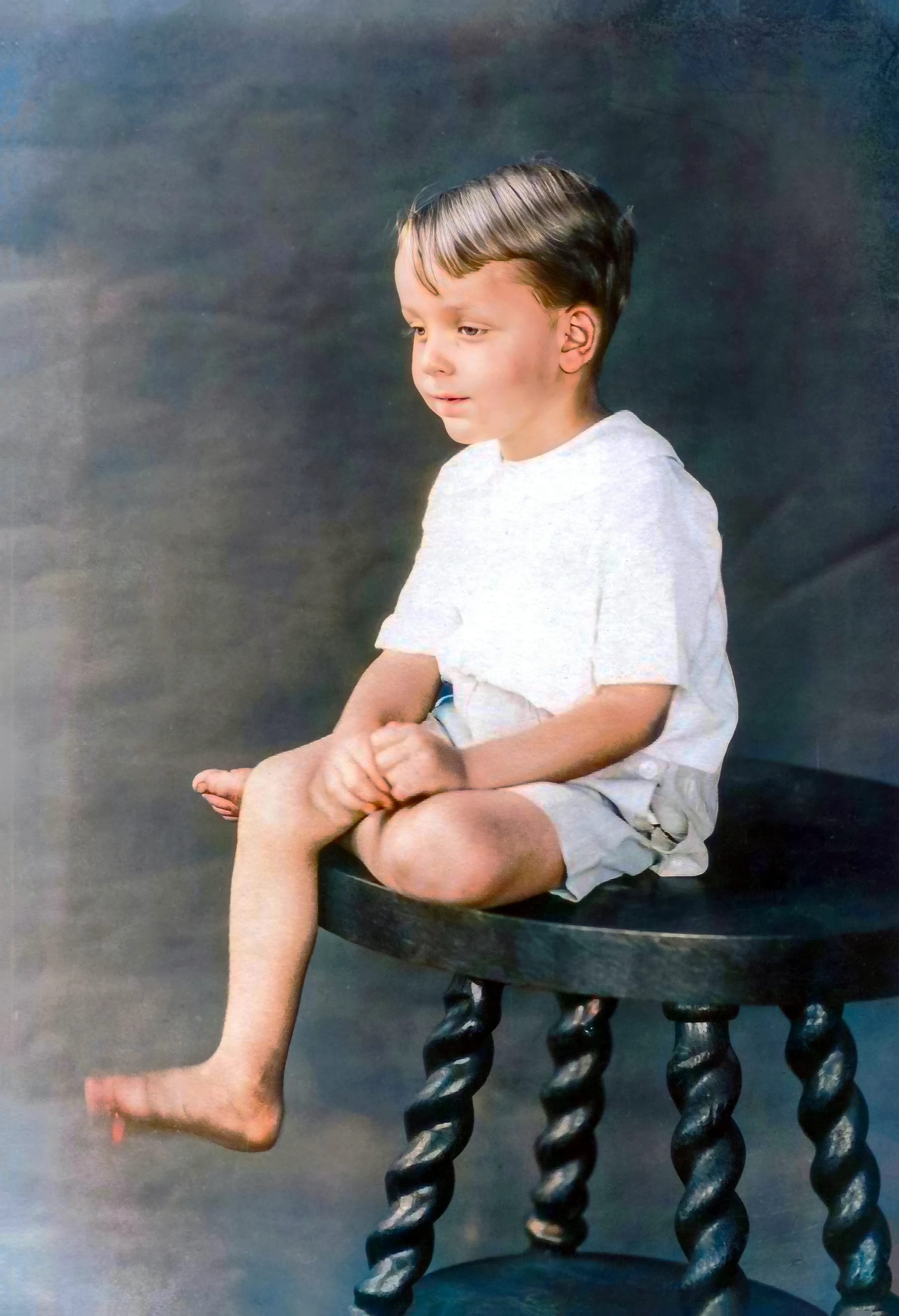 Restored portrait of Big Goose as a young boy, seated barefoot on a carved table in 1923.